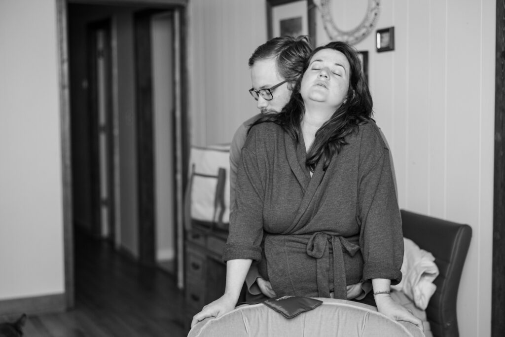 Greensboro Birth Photographer - Husband supports laboring wife's belly through a contraction. 
